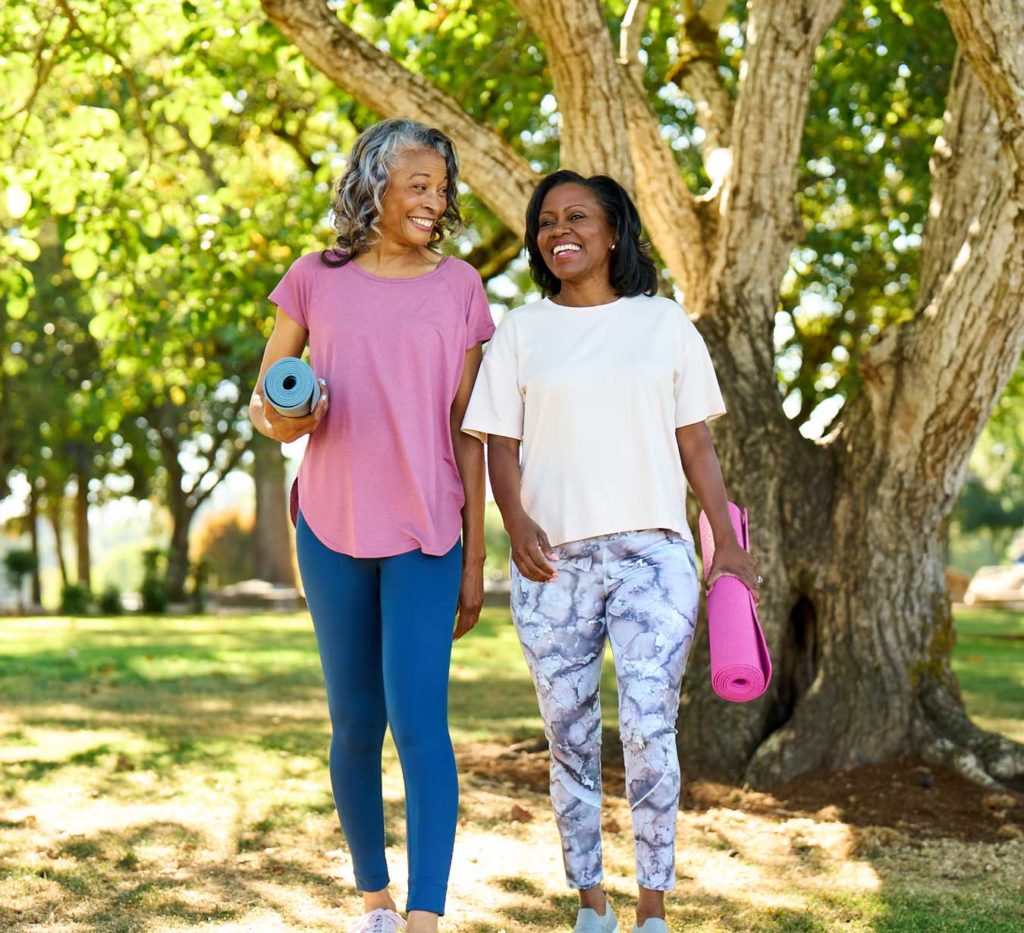 Two women outdoors with yoga mats